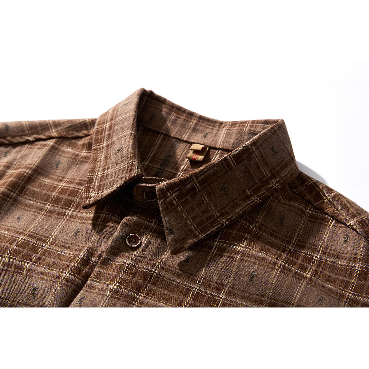Close-up of a brown plaid shirt collar, top buttons and subtle scattered motifs.