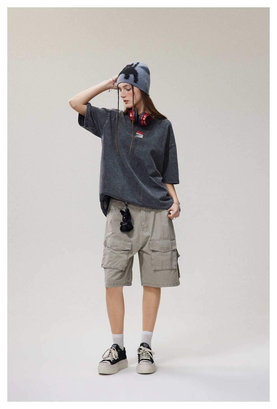 Model wearing an oversized faded charcoal T-shirt with a small chest graphic and light gray cargo shorts.