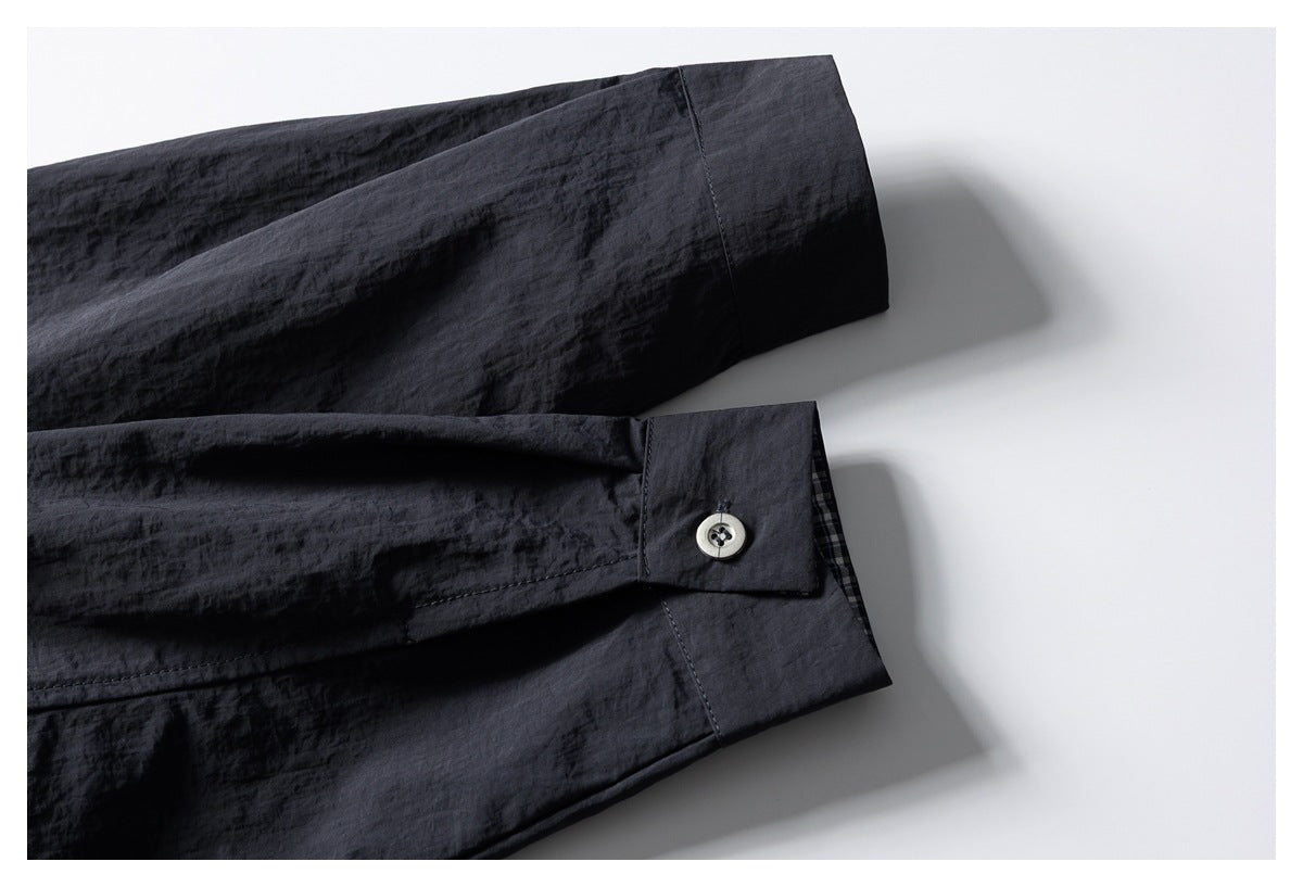 Close-up of a dark garment sleeve cuff with a light-colored button and checked inner trim.