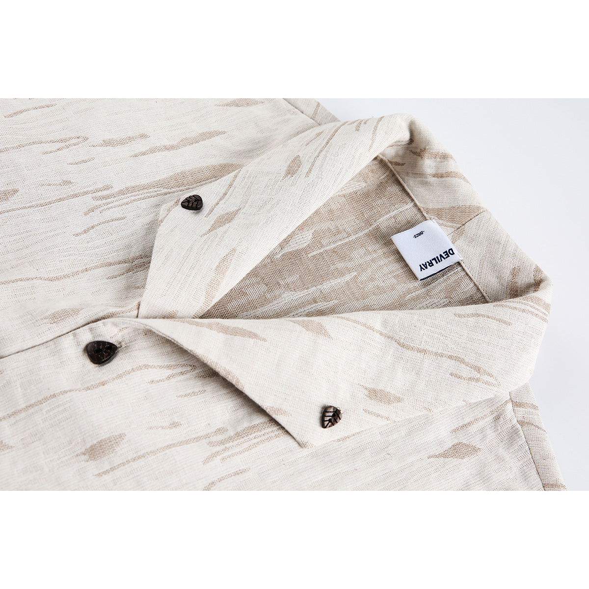 Close-up of an ivory jacket with tan abstract woven stripes, dark buttons, and a sewn inner label.
