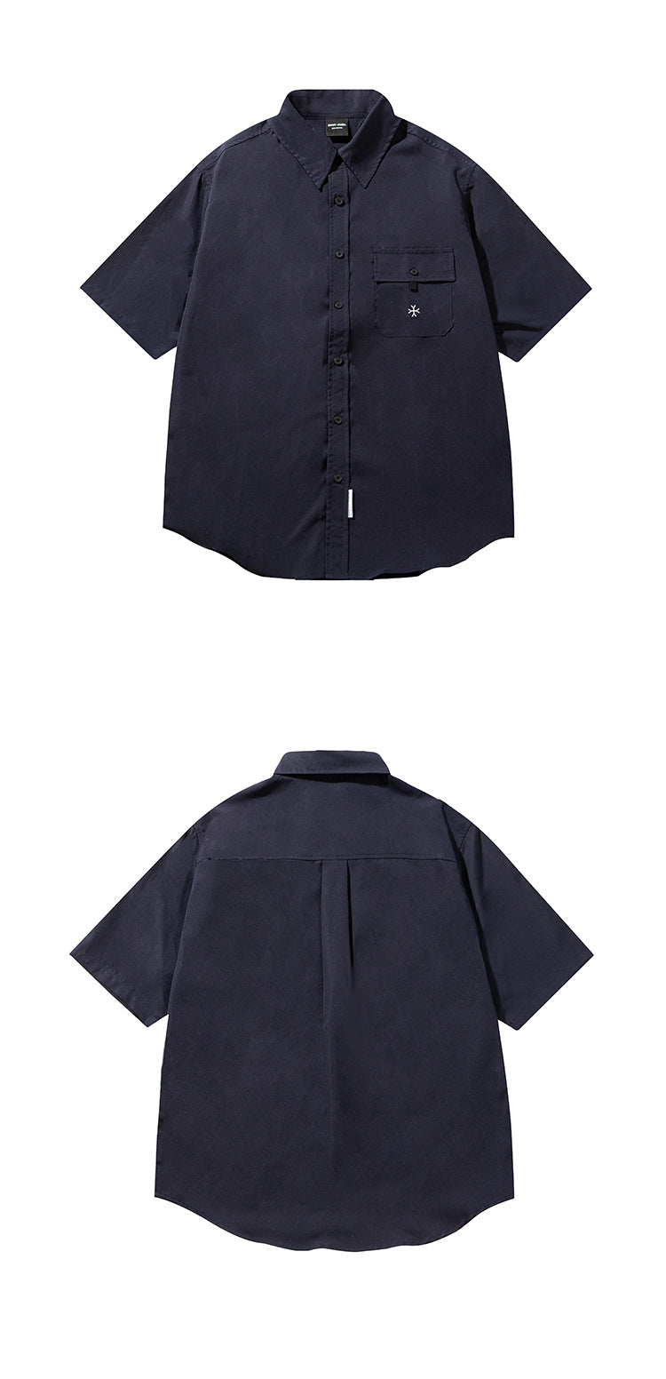 Dark navy short-sleeve button-up shirt shown from the front above its back view; it has a flap chest pocket and curved hem.