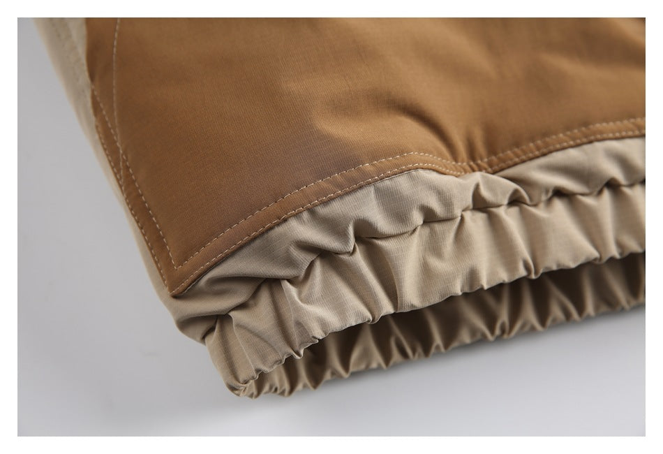 Close-up of the jacket's tan panel and gathered elastic hem in cream and beige.