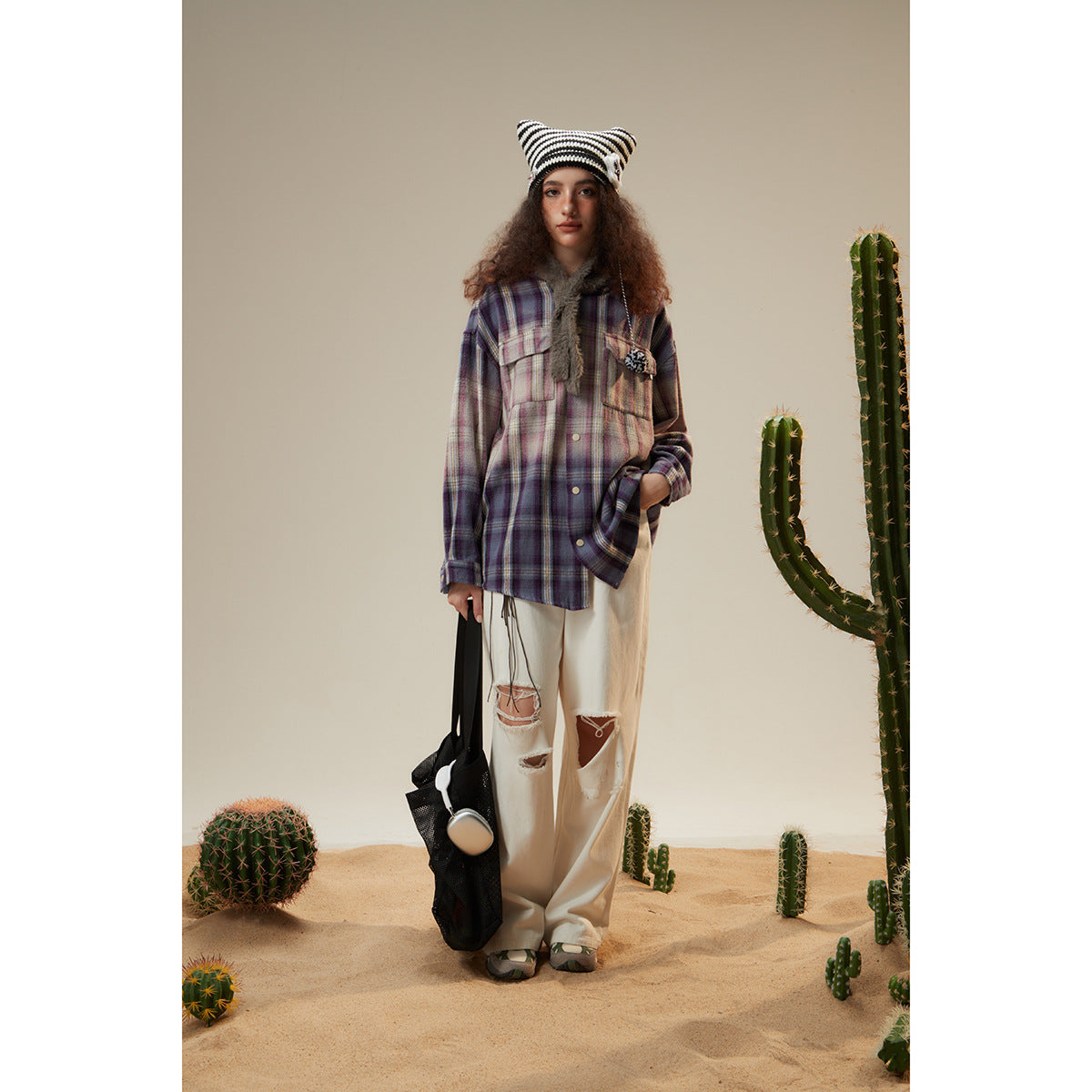 Full-length model wearing a purple plaid shirt jacket, white trousers, and a black-and-white striped beanie.