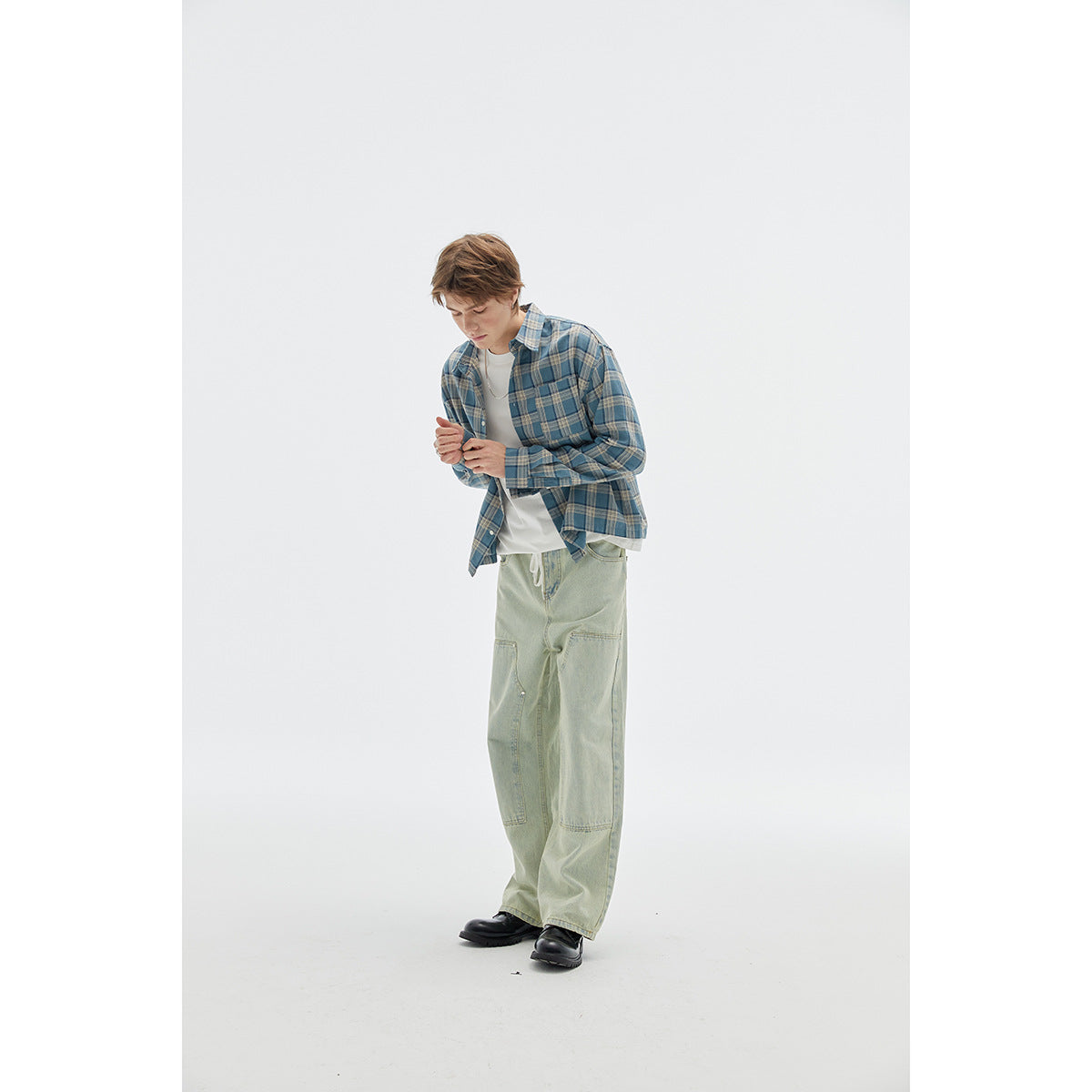 Model wearing a blue plaid button-up shirt over a white tee with pale green wide-leg jeans.