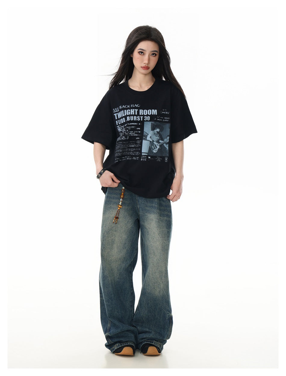 Model wearing an oversized black graphic T-shirt with wide-leg blue jeans, shown full-length from the front.