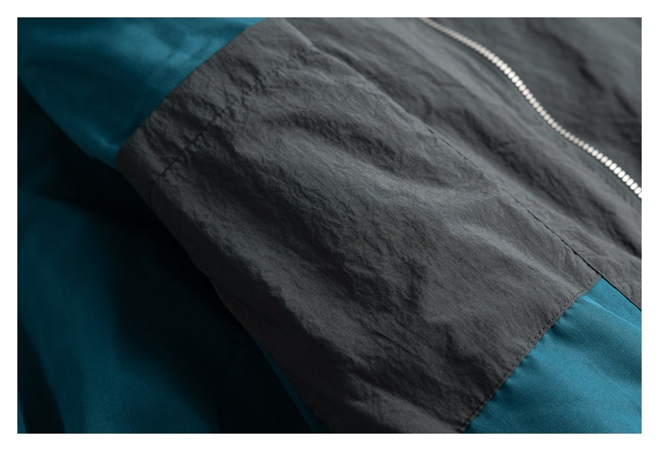 Close-up of a dark charcoal garment with teal panels and a silver zipper.