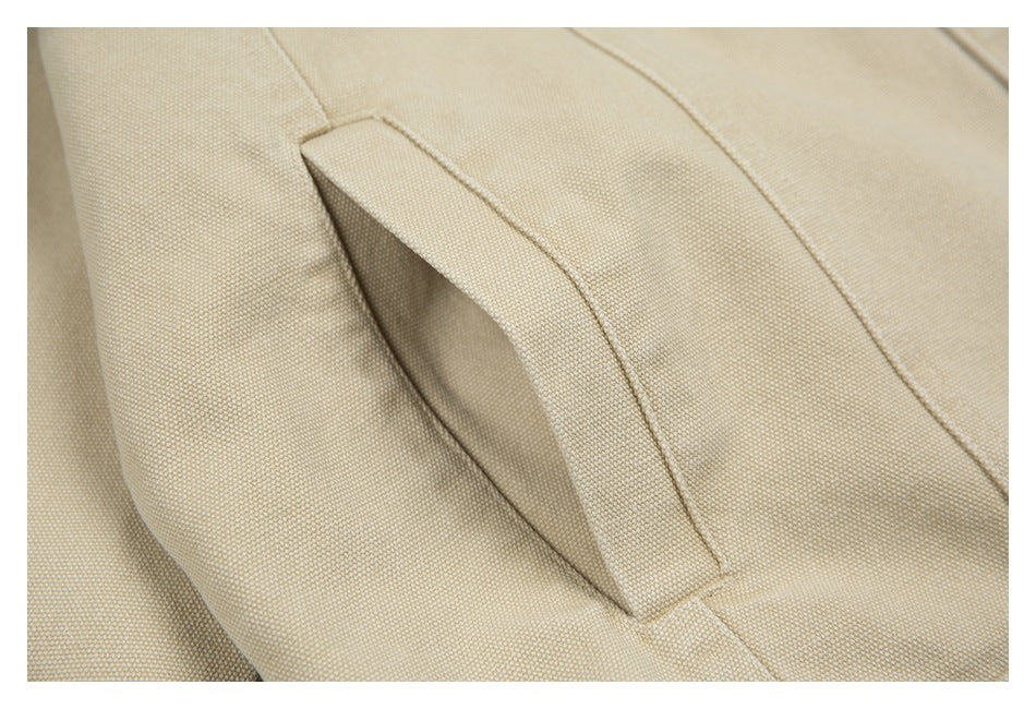 Close-up of a slanted welt pocket opening on beige textured jacket fabric.