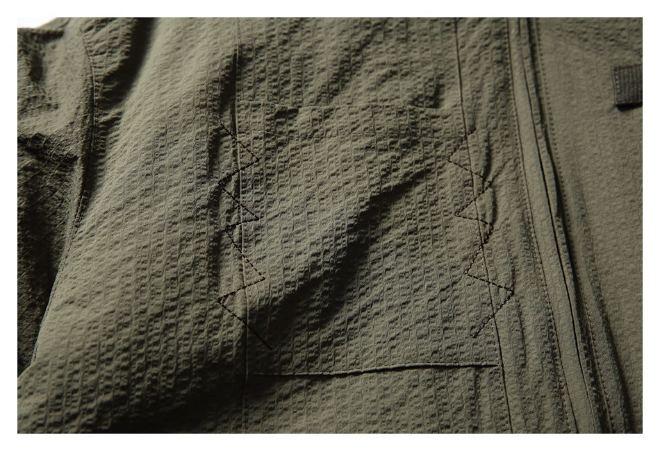 Close-up of a flap pocket with angular stitching on the olive jacket.