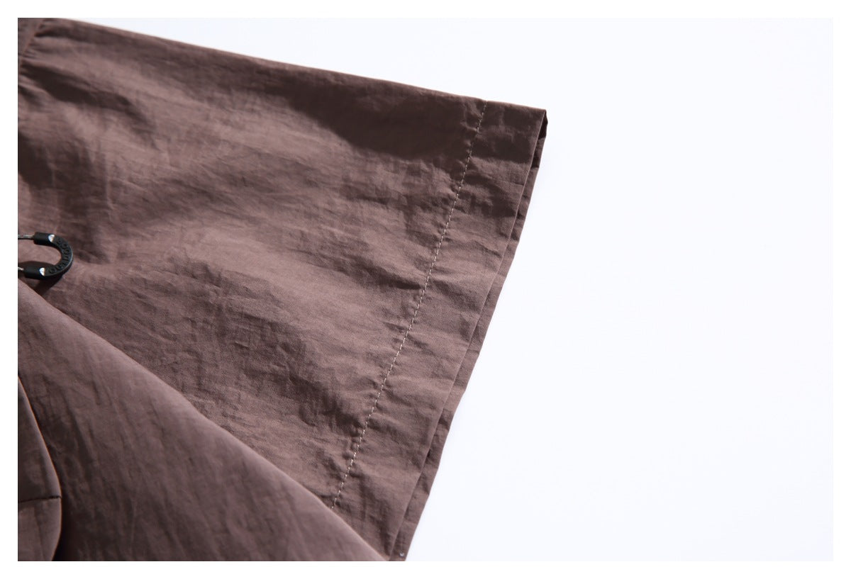 Close-up of a brown jacket sleeve edge and stitched cuff seam against a white background.