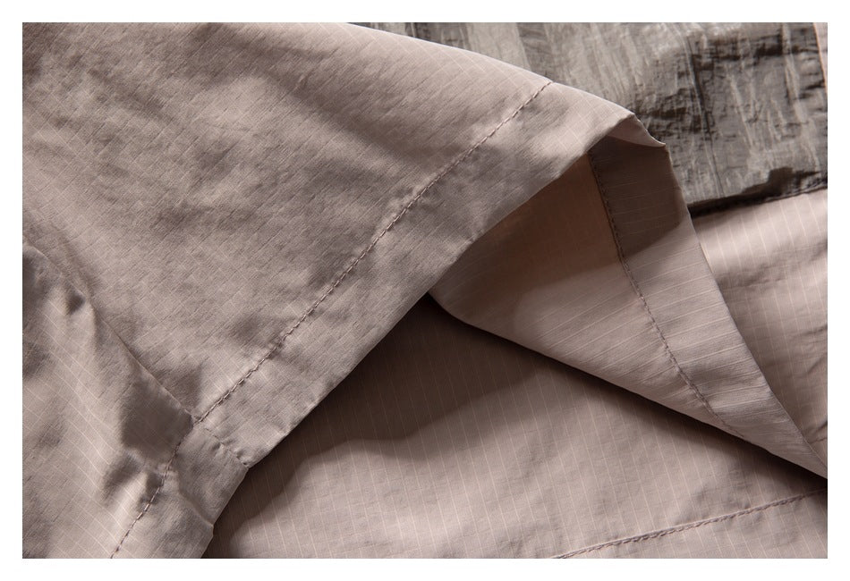 Close-up of a stitched hem and layered light taupe fabric.