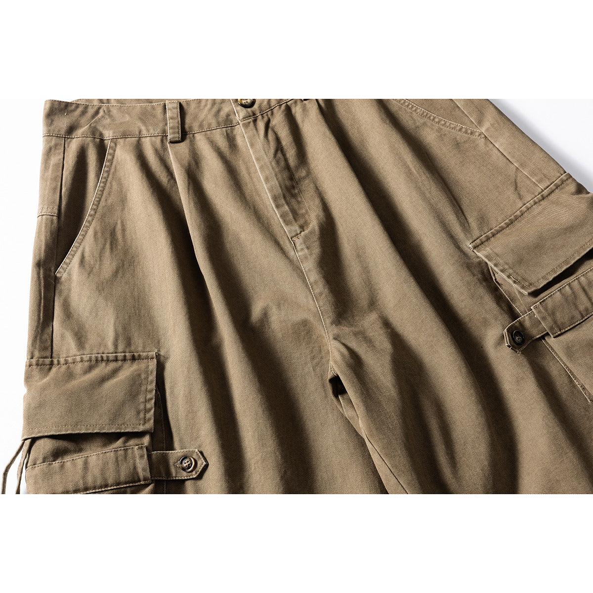 Close-up of khaki-brown cargo shorts with large flap pockets and buttoned adjustment straps.