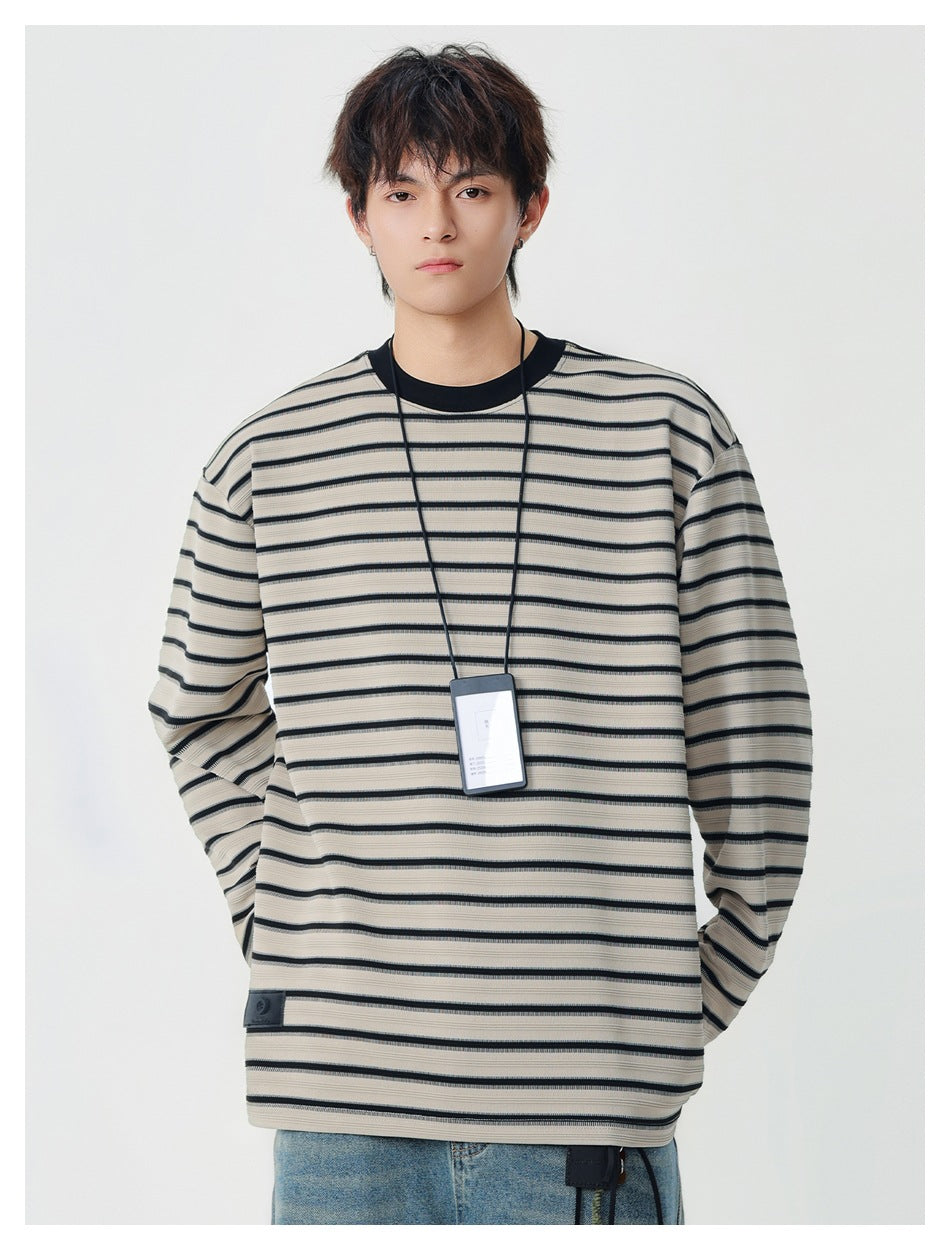 Model wearing a beige long-sleeve shirt with thin black horizontal stripes and a black crew neck.