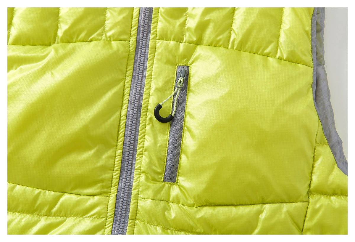 Close-up of a chartreuse quilted vest showing the gray front zipper and a vertical zip pocket.