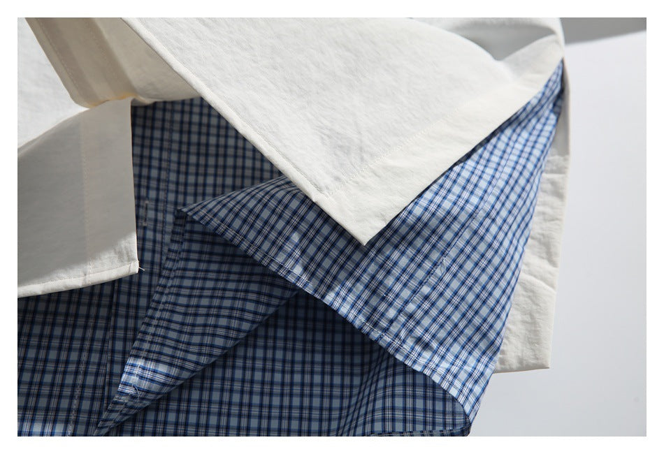 Close-up of a white shirt layered over a blue-and-white checked panel.