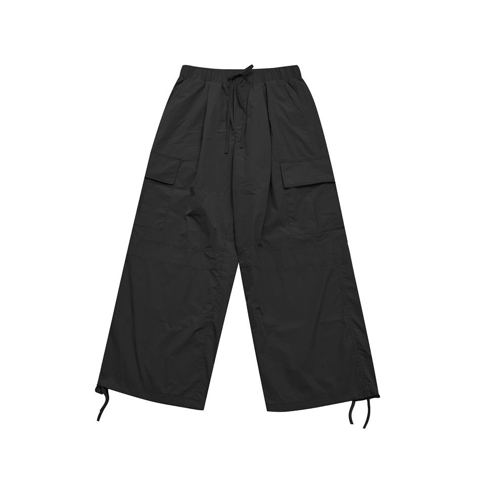 Black wide-leg cargo pants flat lay with elastic drawstring waist, flap thigh pockets and hem drawcords