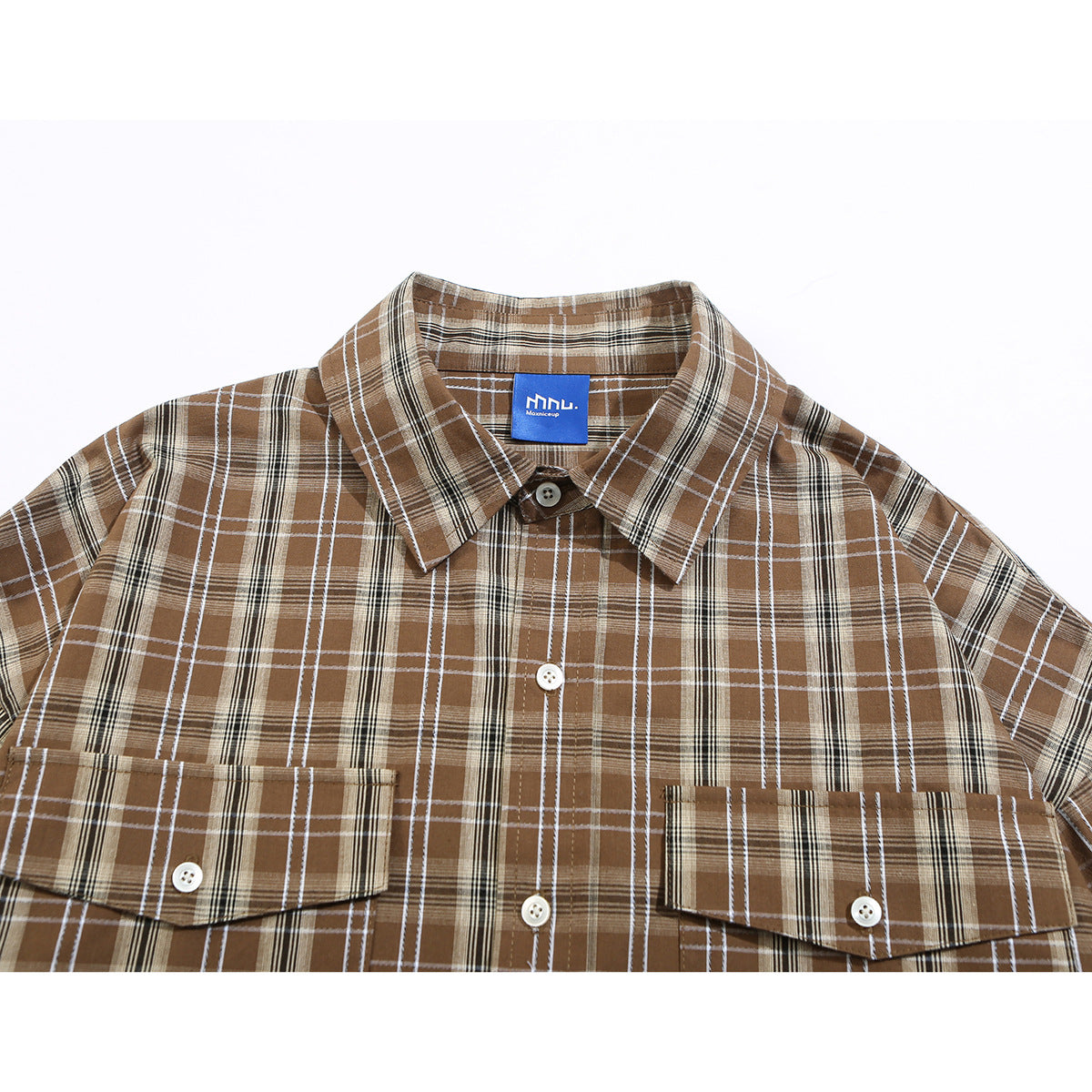 Close-up of a brown plaid button-up shirt showing its collar, buttons, chest pockets, and blue neck label.