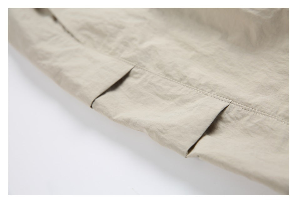 Close-up of a flap pocket and stitched seam on light beige pants.