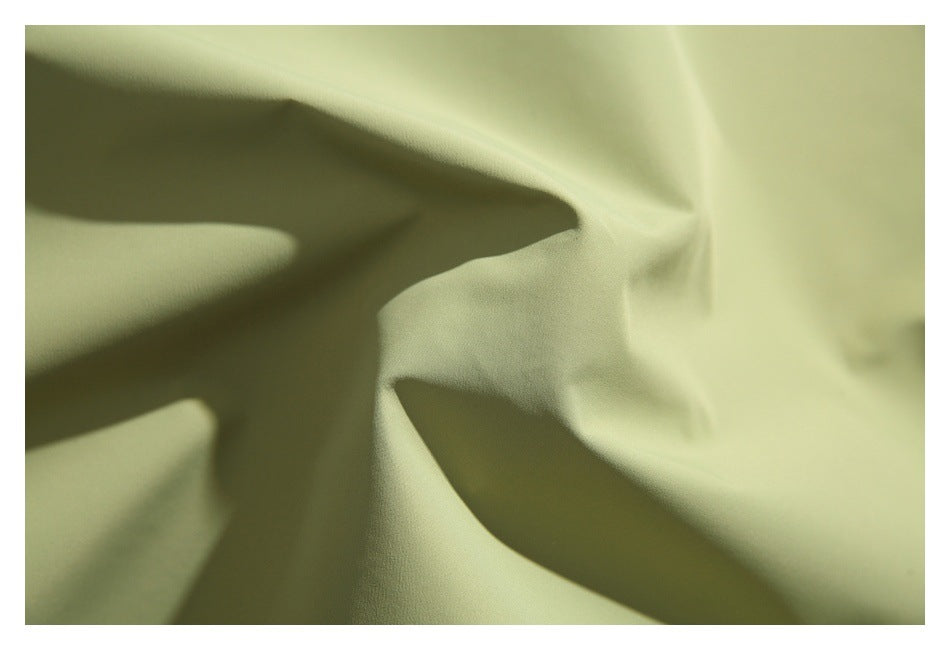 Extreme close-up of the pale olive jacket fabric, showing its surface and folds.