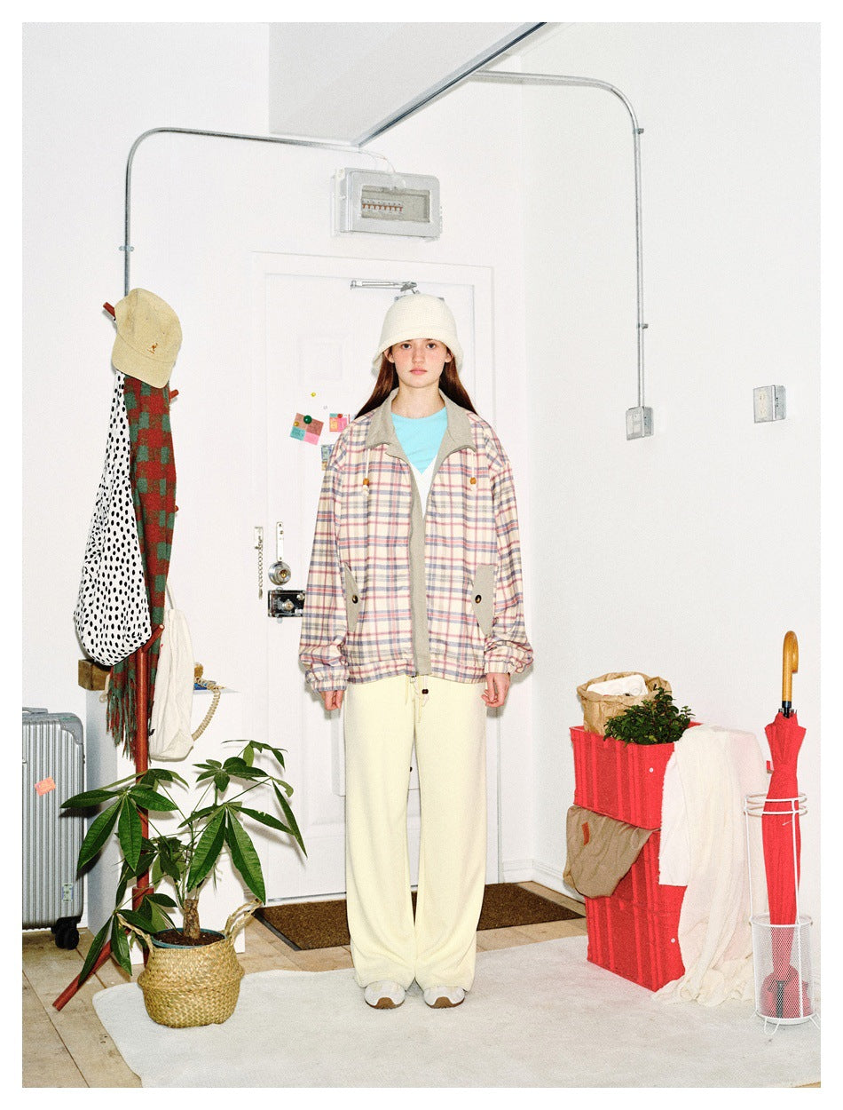 Front view of a model wearing a pastel plaid zip jacket with gray panels and cream wide-leg pants.