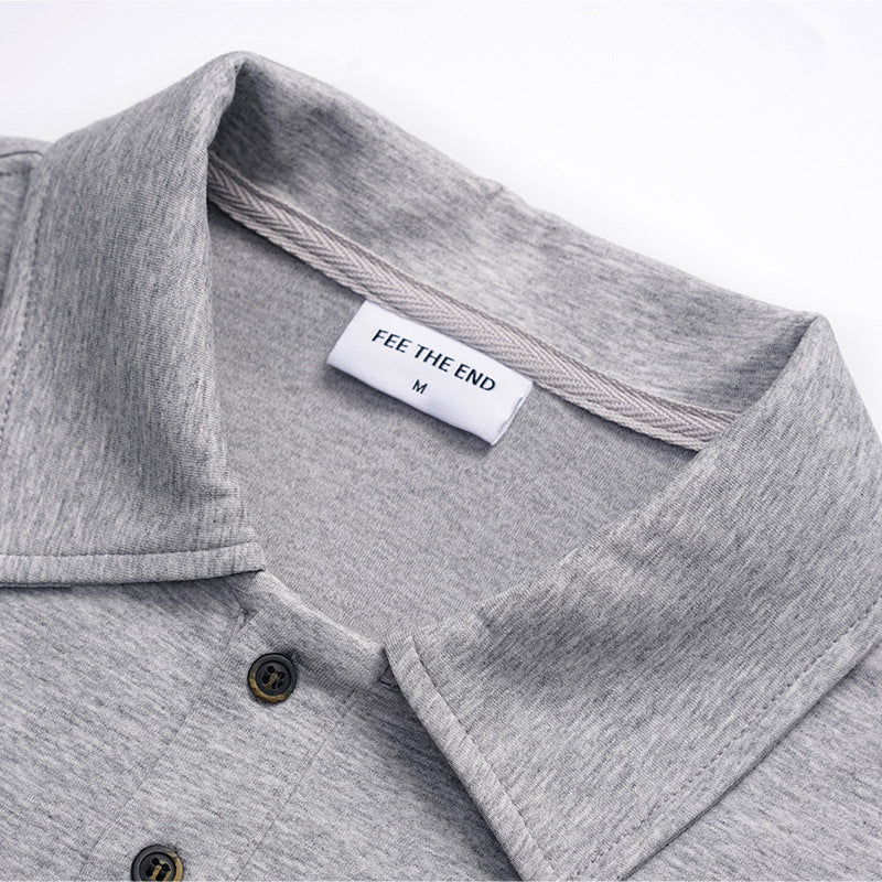 Close-up of a heather gray polo shirt collar, placket, dark buttons and sewn neck label.
