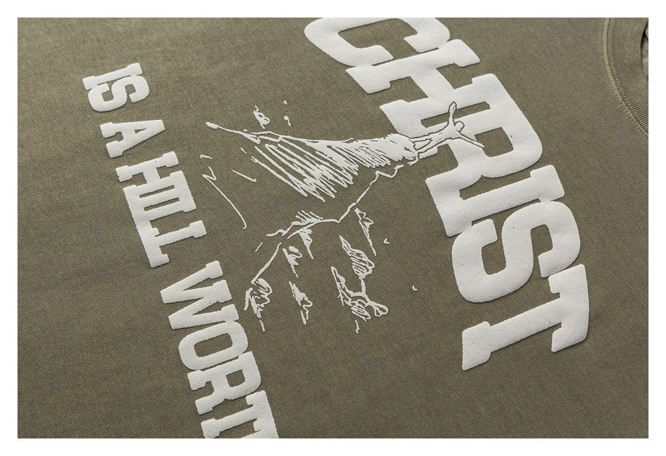 Close-up of the olive shirt’s raised white climber graphic and large lettering.