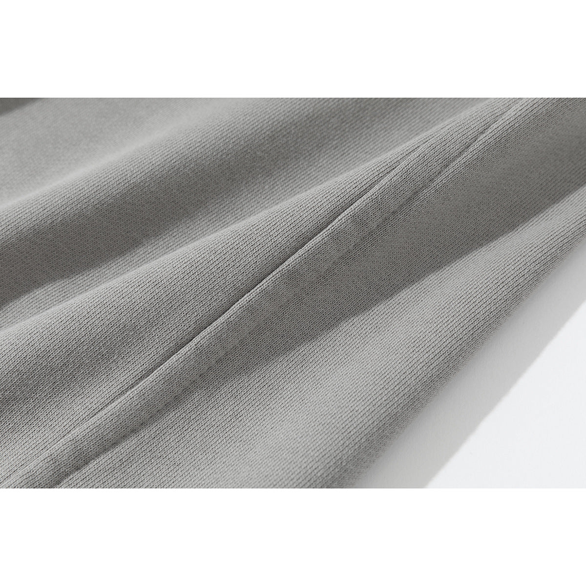 Macro view of the light gray pants fabric and stitched seam.