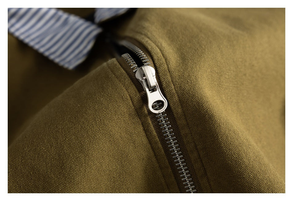 Close-up of a silver zipper on textured olive-brown jacket fabric, with striped lining visible.
