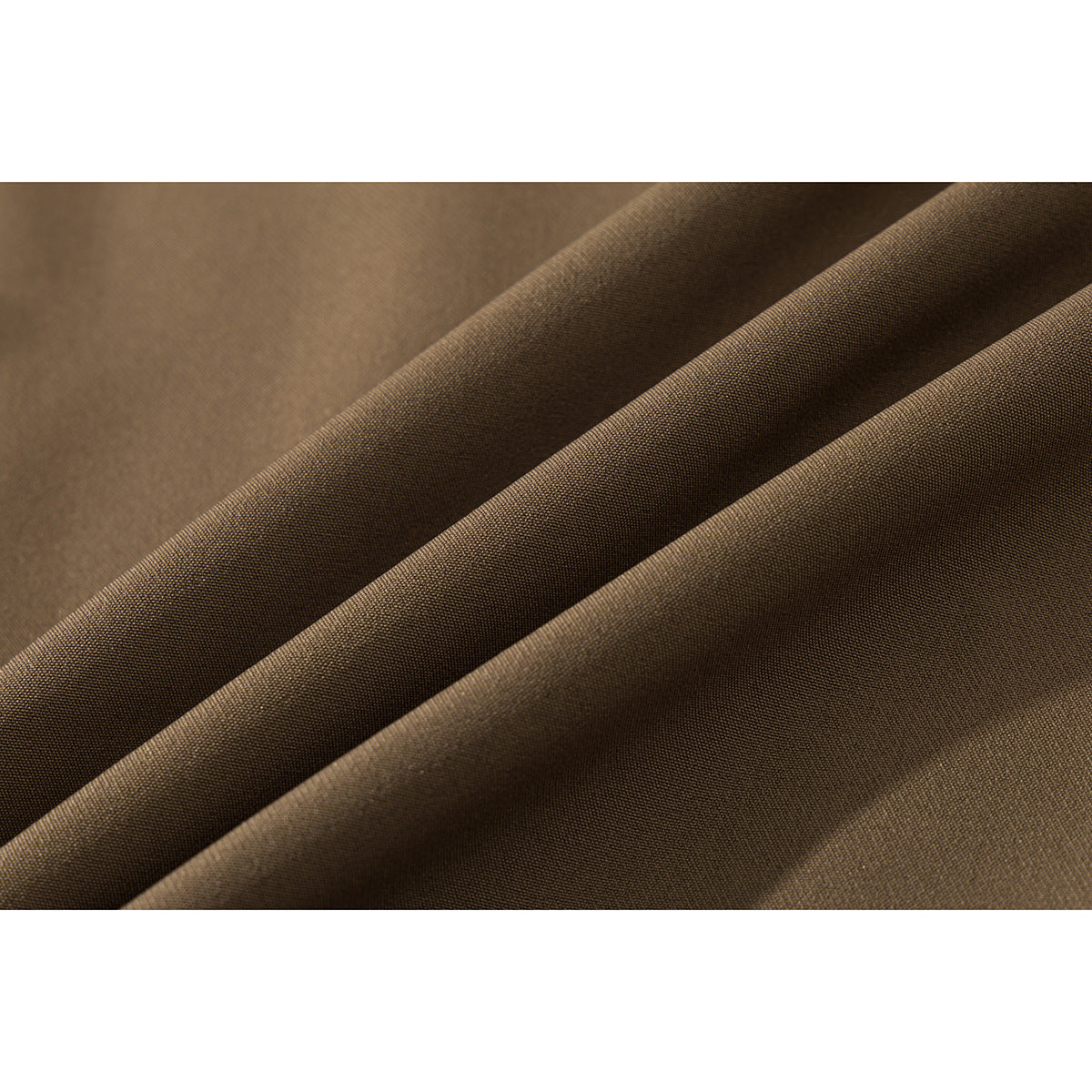 Macro view of brown shirt fabric arranged in diagonal folds, showing its fine surface texture.