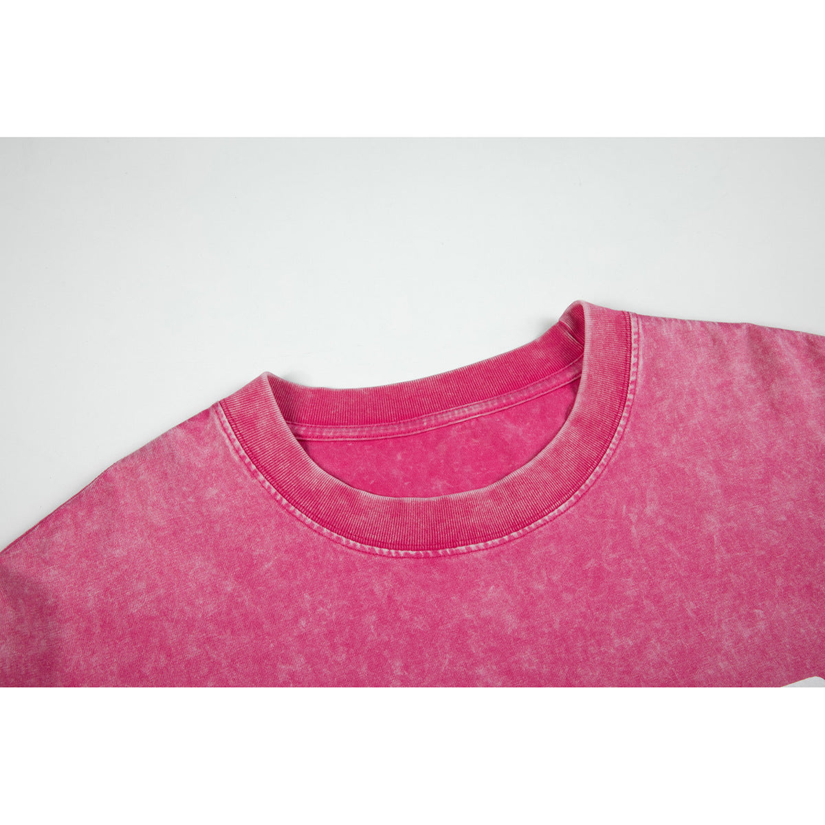 Close-up of the pink acid-wash T-shirt's ribbed crew neckline and shoulder seams.