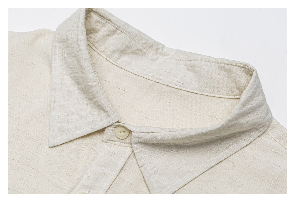 Close-up of the off-white shirt's pointed collar, neckline stitching, and top button.