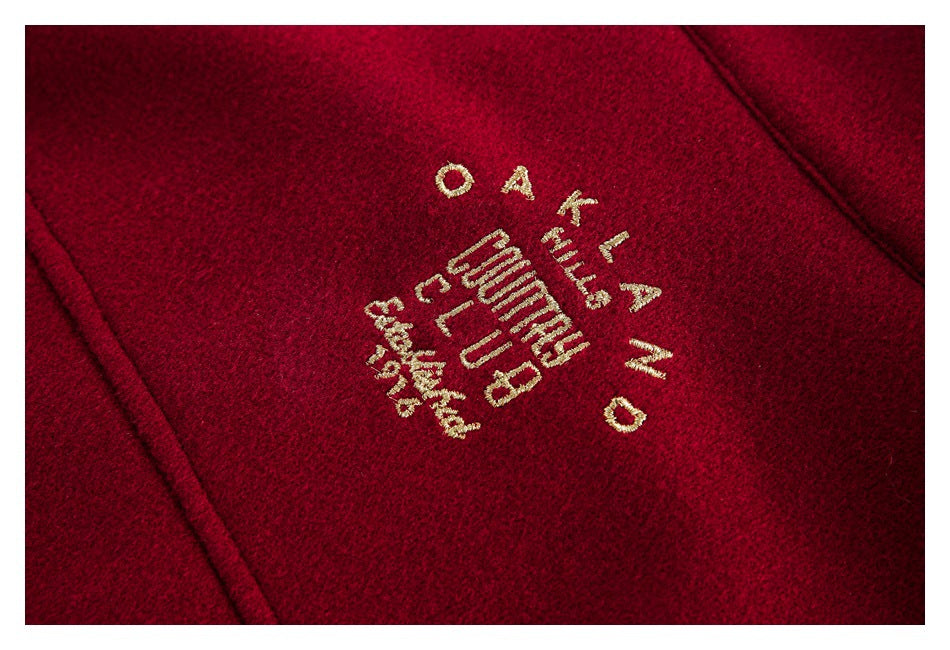 Close-up of gold embroidered lettering on burgundy fabric.