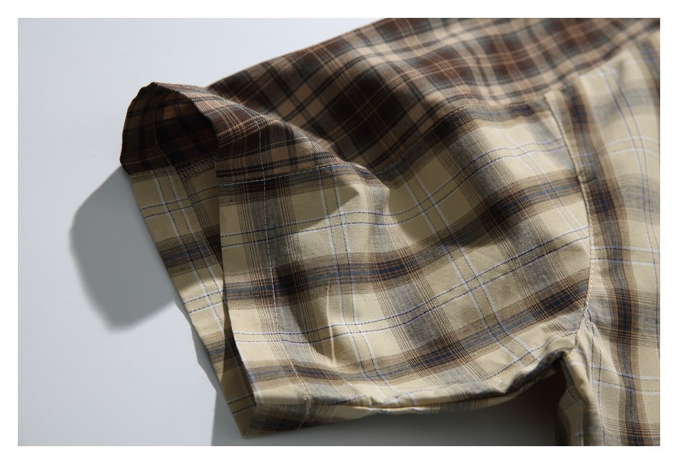 Close-up of a short sleeve showing the tan, brown, and blue plaid pattern and hem.
