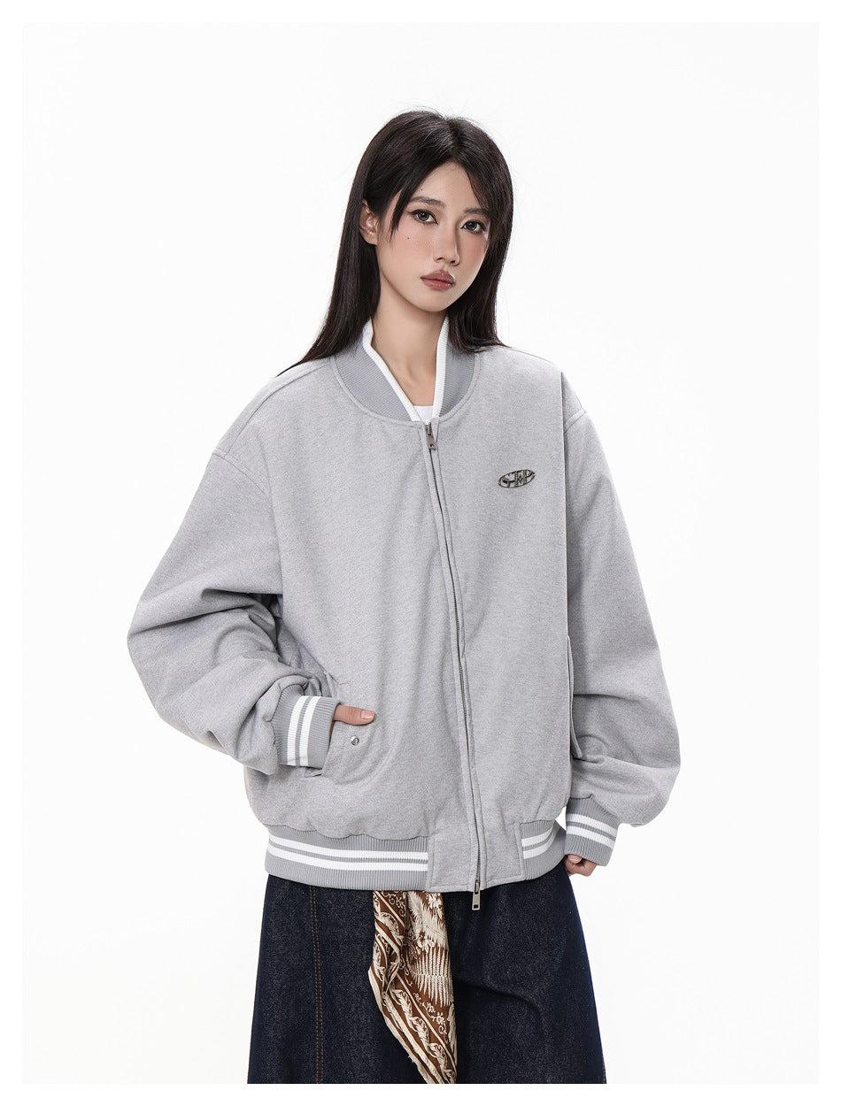 Closer front view of a model in a light gray bomber jacket with a zipper, side pockets, striped trim, and chest emblem.