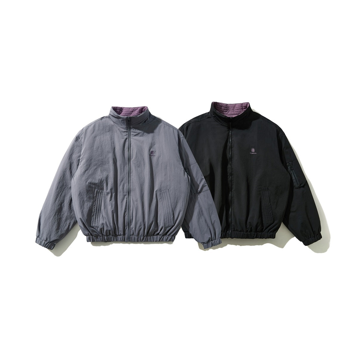 Front view of two zip-front jackets, one gray and one black, with stand collars and elastic hems.