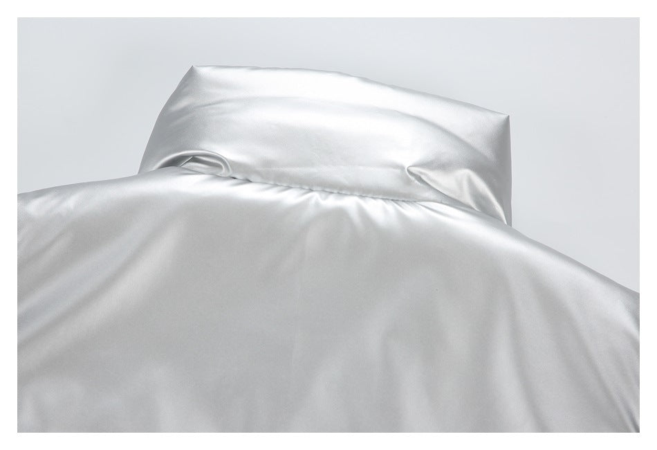 Close-up of glossy silver fabric with a folded rectangular panel and stitched seam.