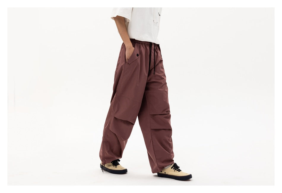 Front-side view of a model wearing loose mauve cargo pants with an elastic drawstring waist and layered leg pockets.