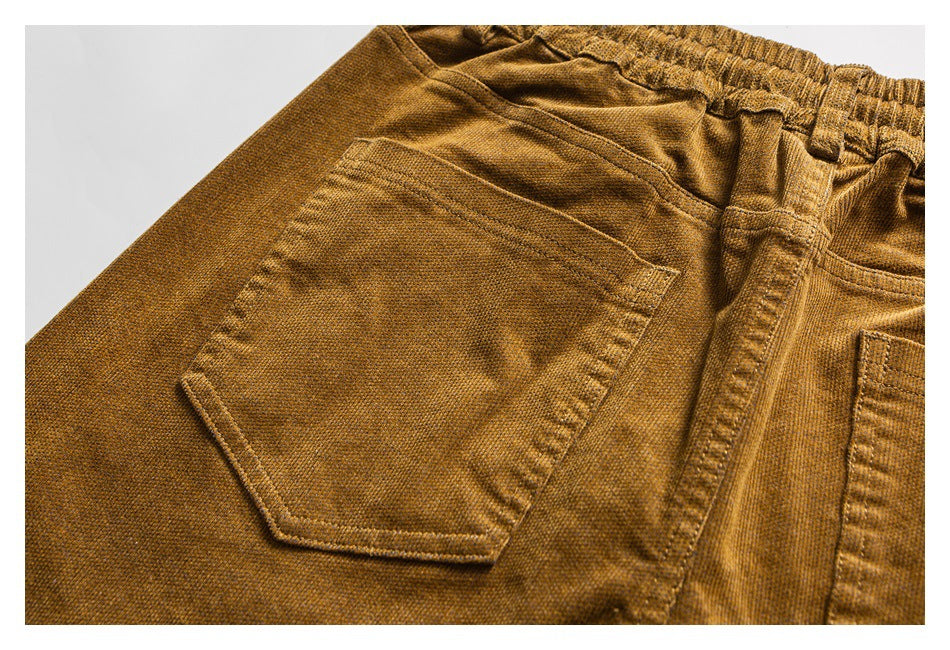 Close-up of mustard-brown pants showing an angular rear pocket, waistband, belt loops and stitching.