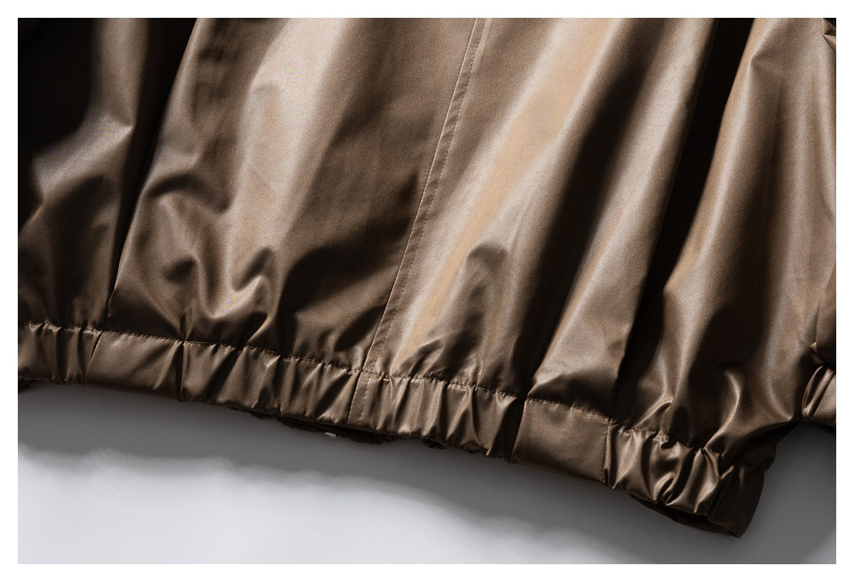 Close-up of the taupe-brown jacket's gathered elastic hem and shiny fabric.