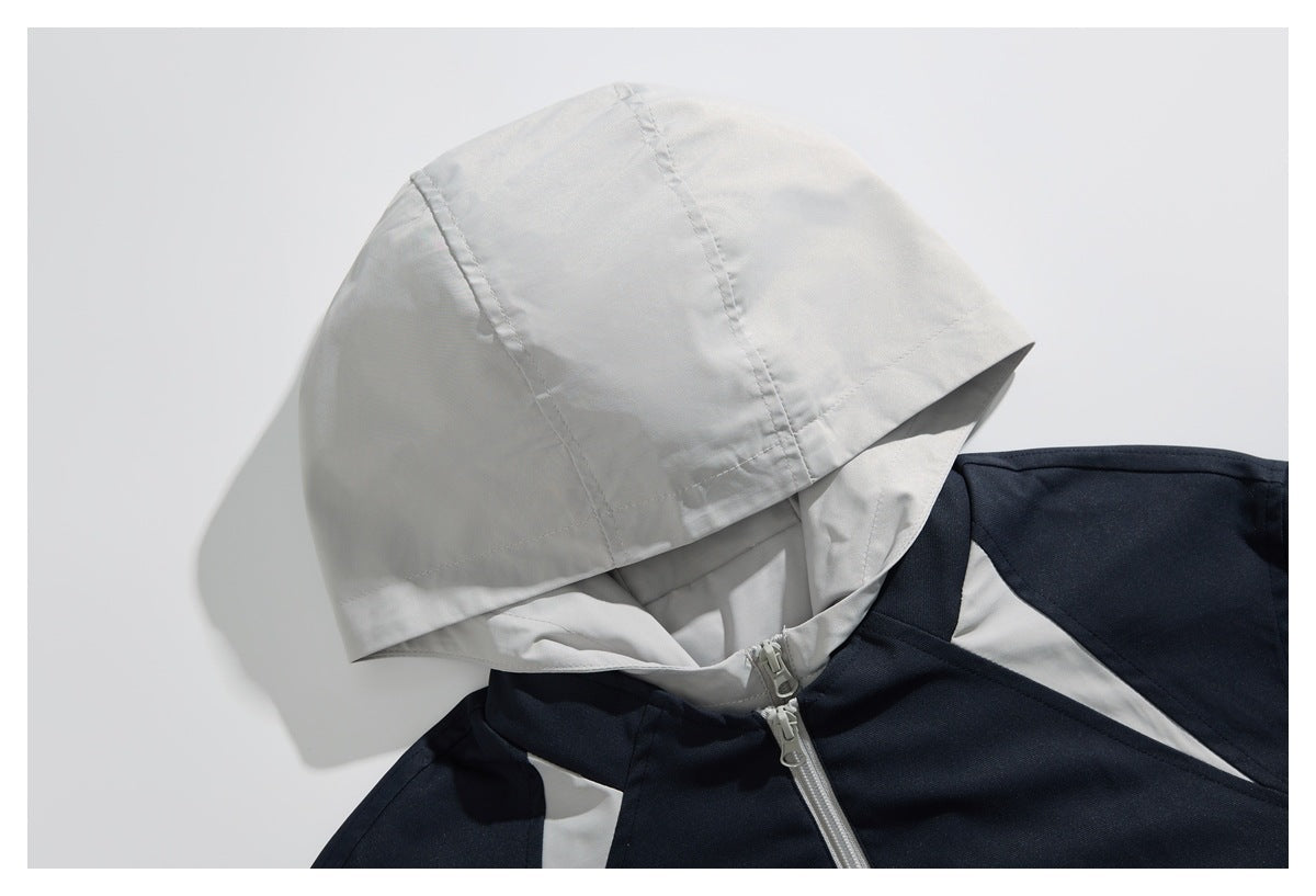 Close-up of a light gray hood and contrasting shoulder panels on a navy jacket, showing the front zipper.