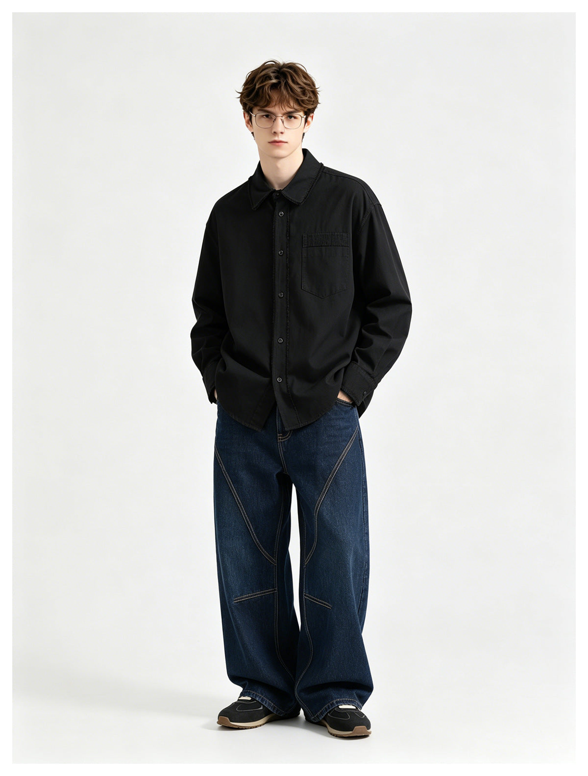 Model wearing a black button-front shirt with a chest pocket and oversized dark blue jeans.