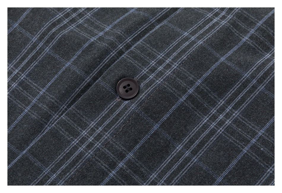 Close-up of a dark button on charcoal plaid shirt fabric.