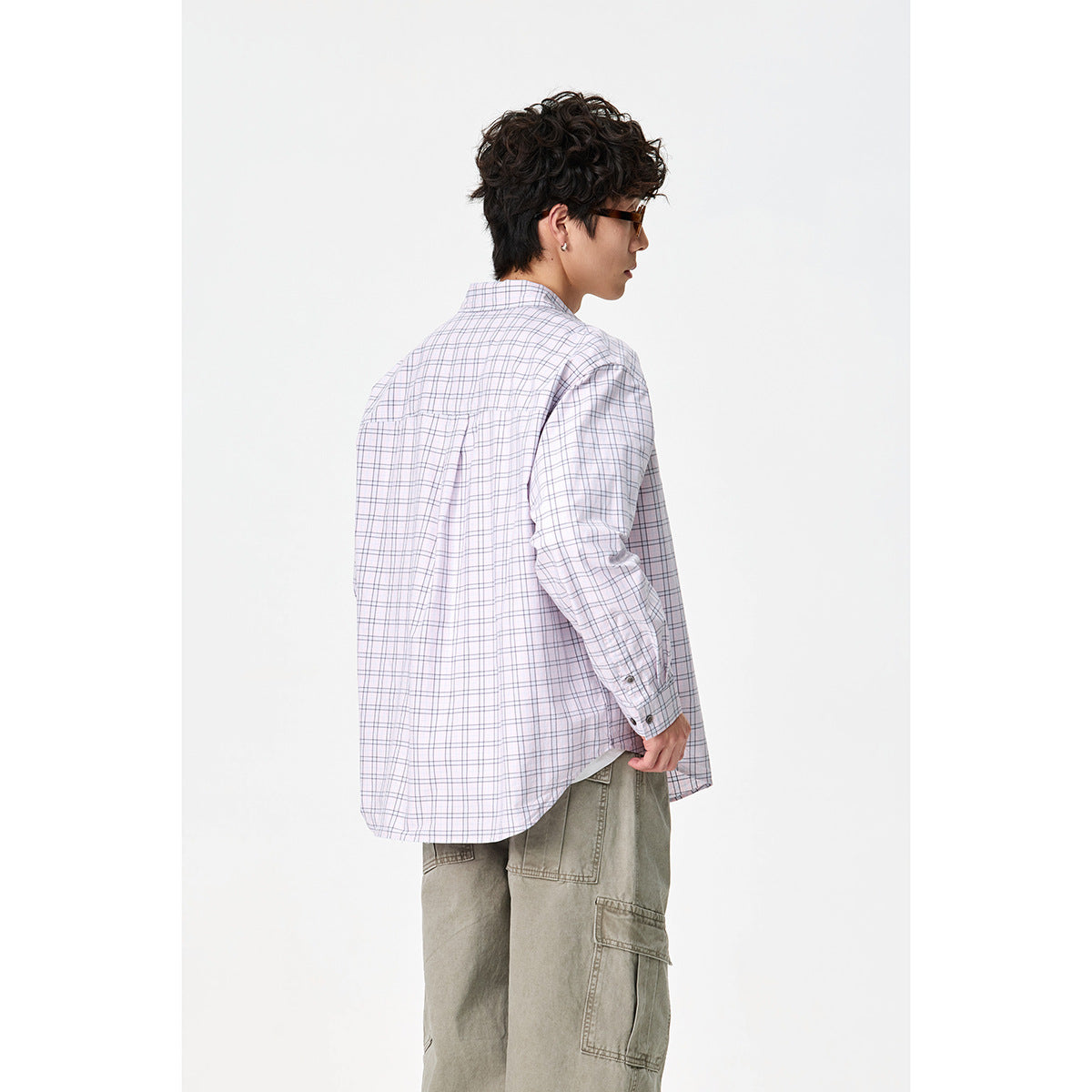 Rear view of a model wearing a pale lavender plaid button-down shirt with a back yoke and pleat.