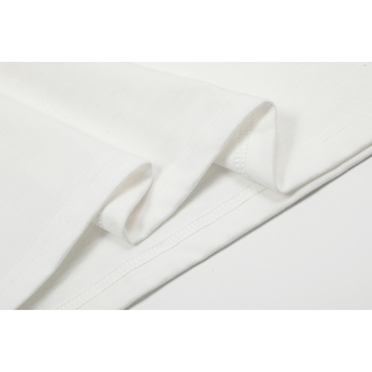 Close-up of the white T-shirt fabric folded to show its stitched hem.