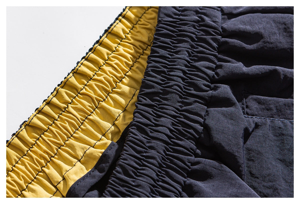 Close-up of a gathered dark waistband beside a mustard-yellow elasticized panel and dark fabric.