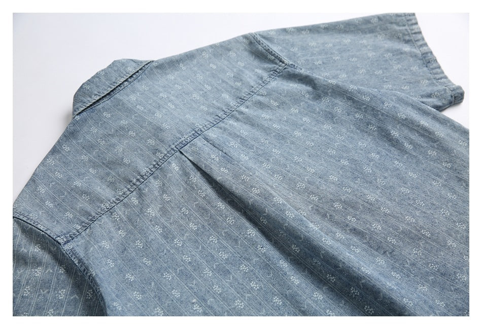 Close-up of blue fabric with a small white geometric pattern and visible garment seams.