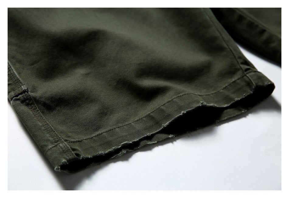 Close-up of the stitched hem on olive green trousers.