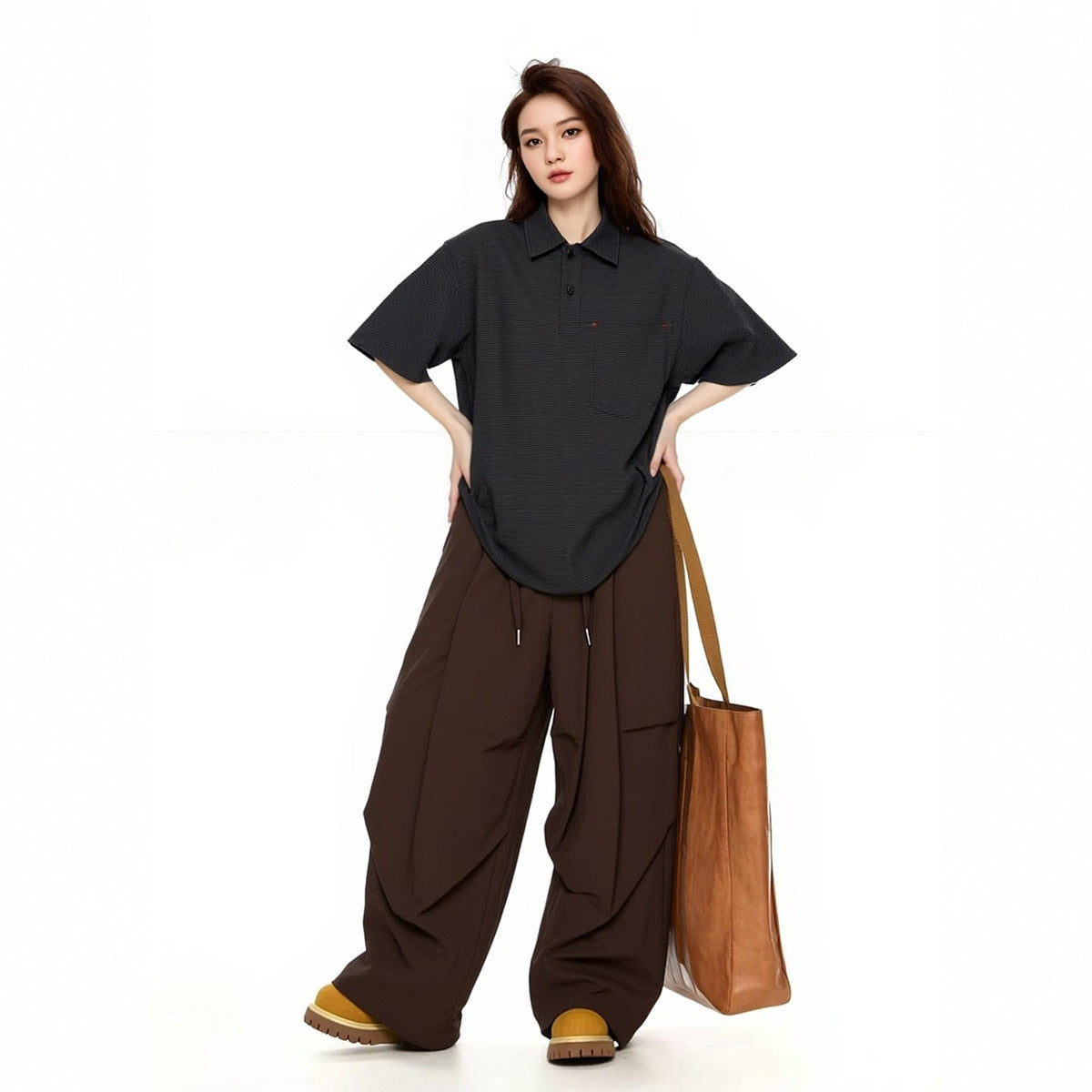Model wearing an oversized black pinstriped polo with a chest pocket and loose dark brown trousers.
