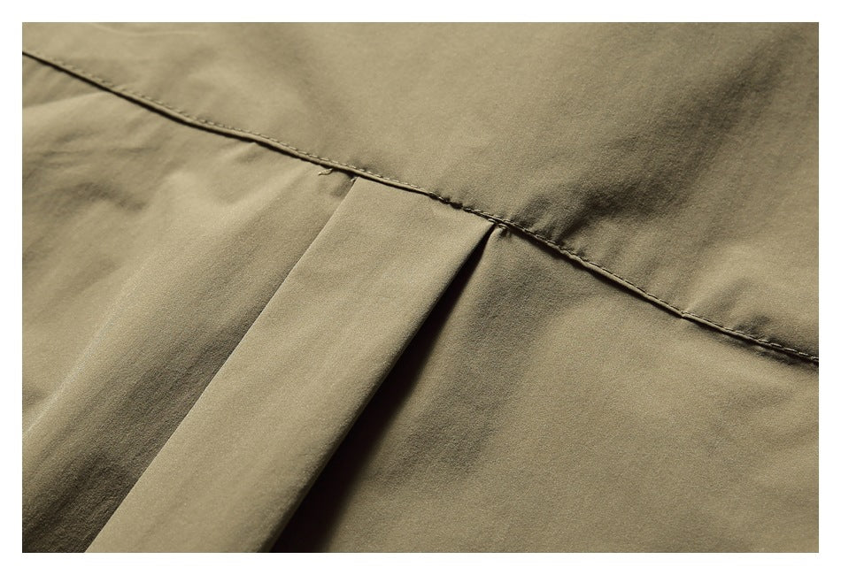 Close-up of olive-khaki garment fabric showing a stitched seam and folded panel.