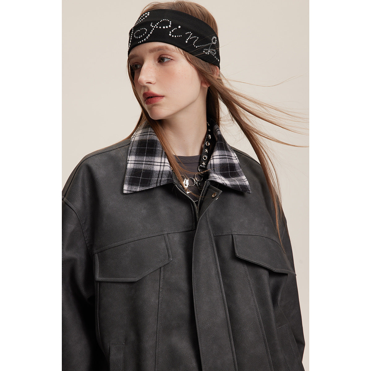 Close view of a model wearing a black jacket with a black-and-white plaid collar and flap pockets.