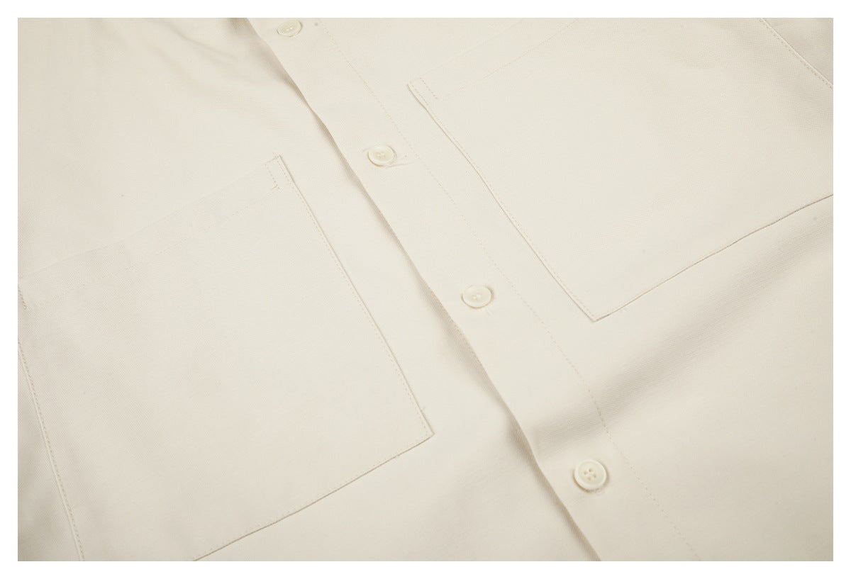 Close-up of the off-white shirt front, showing its button placket and two patch pockets.
